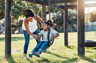 Buy stock photo Full length shot of a mother pushing her daughter on a swing at the park