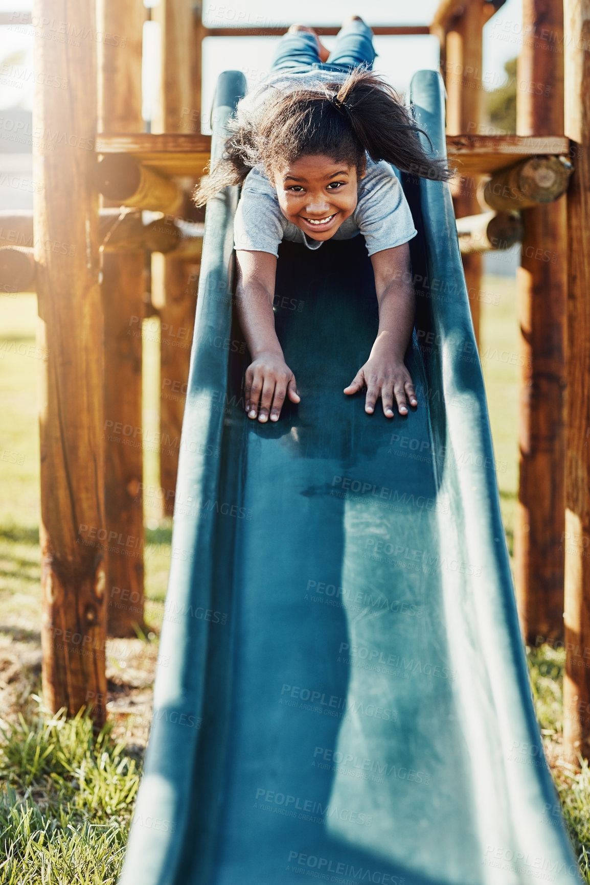 Buy stock photo Slide, playing and portrait of kid in park for fun, joy or summer break in countryside. Happy, excited and girl child on obstacle equipment in outdoor playground with smile for school holiday.