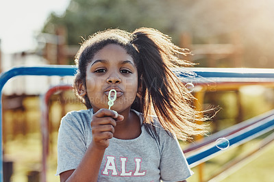 Buy stock photo Cropped portrait of an adorable little girl blowing bubbles at the park