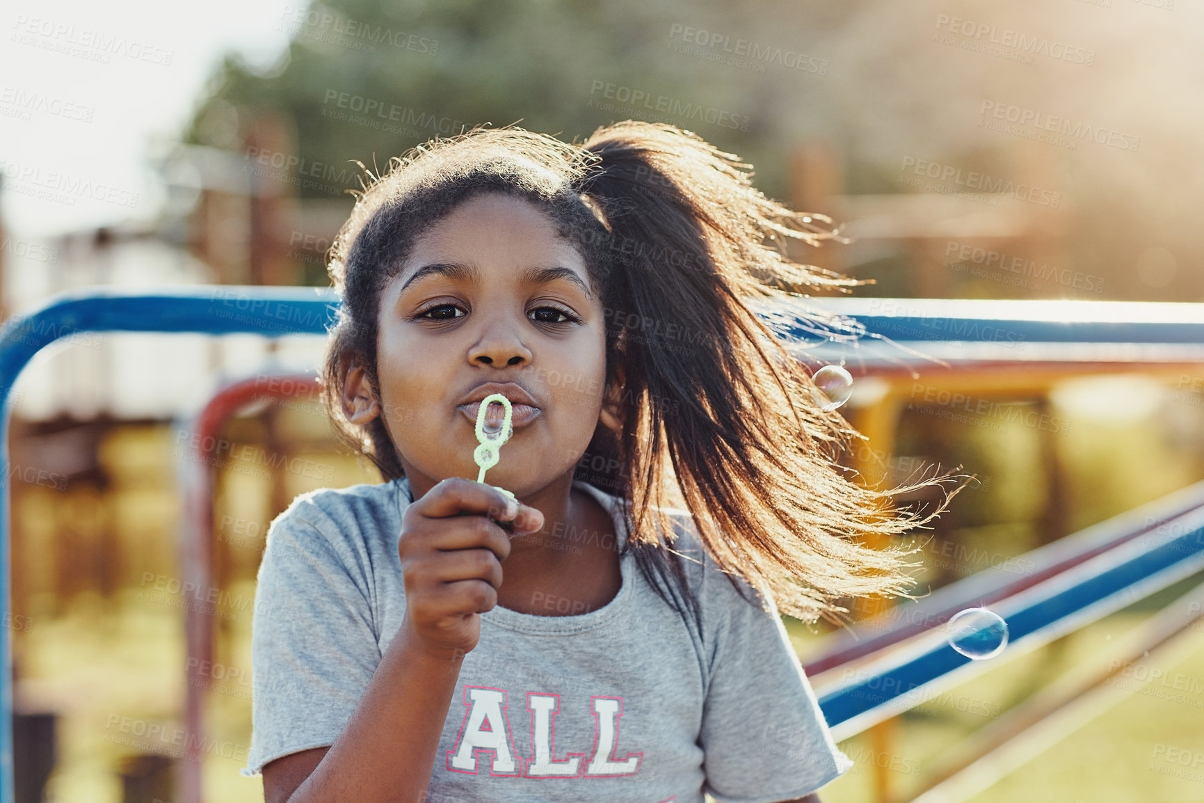 Buy stock photo Cropped portrait of an adorable little girl blowing bubbles at the park