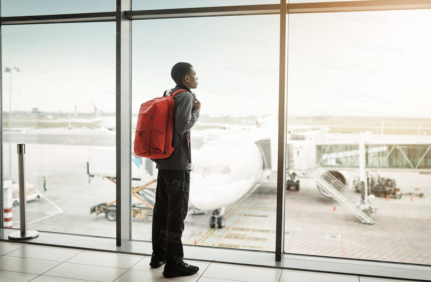 Buy stock photo Rearview shot of a young man looking through the window at an airport
