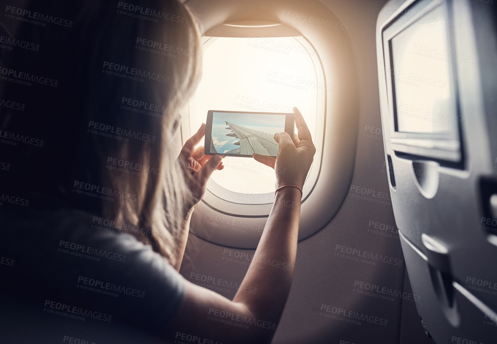 Buy stock photo Cropped shot of an unrecognizable young woman taking photos while sitting in an airplane