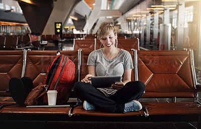 Buy stock photo Full length shot of an attractive young woman using a tablet in an airport