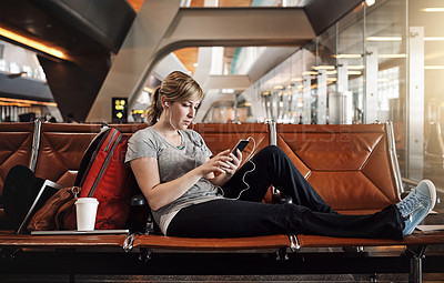 Buy stock photo Full length shot of an attractive young woman using a cellphone in an airport