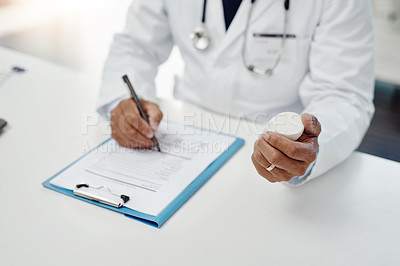 Buy stock photo High angle shot of an unrecognizable male doctor writing on a form while holding medication in his office