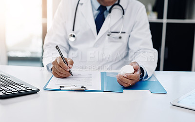 Buy stock photo Cropped shot of an unrecognizable male doctor writing on a form while holding medication in his office
