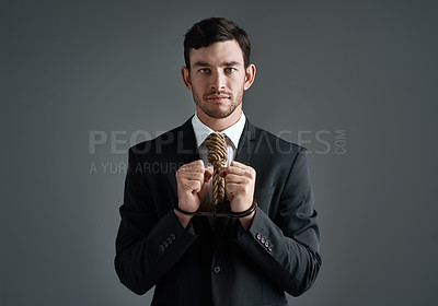 Buy stock photo Studio portrait of a handcuffed businessman with a noose tied around his neck for a tie against a gray background