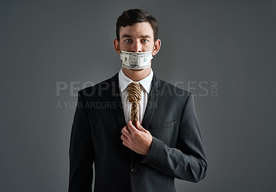 Buy stock photo Studio portrait of a businessman with rope around his neck and money taped over his mouth against a gray background