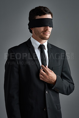 Buy stock photo Studio shot of a young businessman wearing a blindfold against a gray background