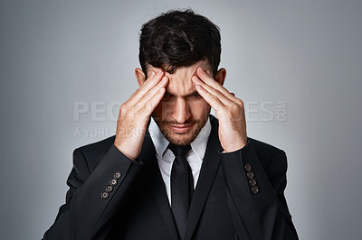 Buy stock photo Studio shot of a young businessman suffering from a headache against a grey background