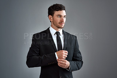 Buy stock photo Studio shot of a handsome young businessman dressed in a suit against a grey background