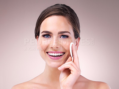 Buy stock photo Studio portrait of an attractive young woman using a cotton pad on her face against a pink background