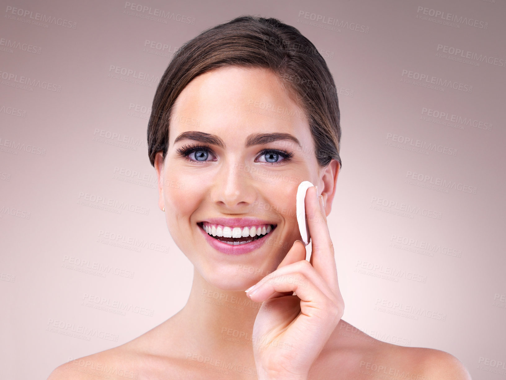 Buy stock photo Studio portrait of an attractive young woman using a cotton pad on her face against a pink background