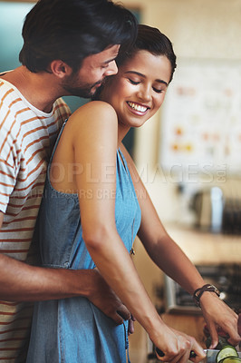 Buy stock photo Shot of an affectionate young couple cooking together in their kitchen at home