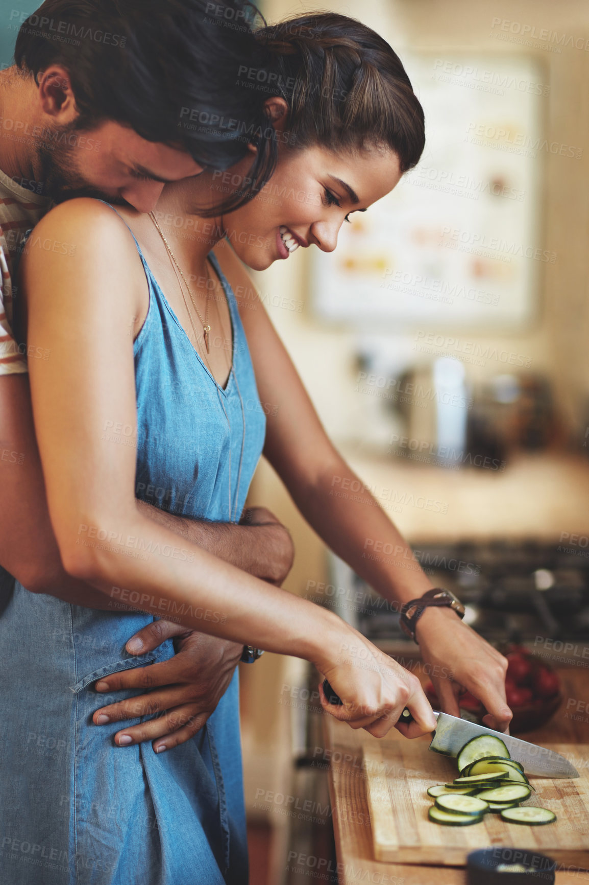 Buy stock photo Home, couple and hug with knife, vegetable and food cutting in kitchen with smile, love and care. Cooking, salad and cucumber with happy people with bonding, support and marriage with wellness