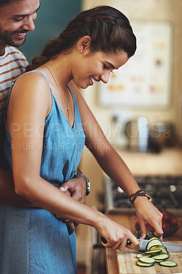 Buy stock photo Man, woman and hug with knife for cooking in kitchen, care and diet with smile to prepare lunch in home. Indian people, happy couple and embrace with cucumber, love and meal prep for dinner in house