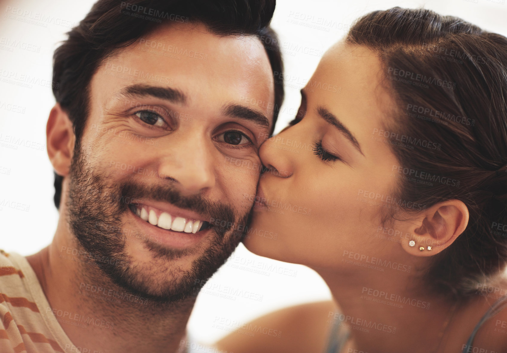 Buy stock photo Couple, home and kiss with playful, fun and romance with smile, bonding and love together. Young man, woman and cheerful face for relaxing with care, happiness and break in house or apartment lounge