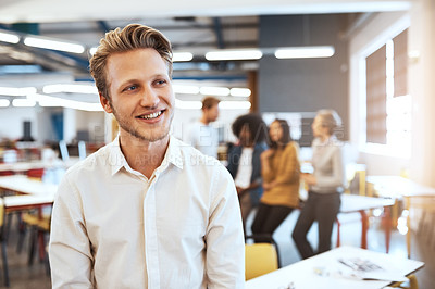 Buy stock photo Cropped shot of a handsome young businessman in the office with his colleagues in the background