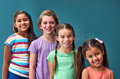 Buy stock photo Line, happy and portrait of children on blue background for back to school, education and academy. Students, youth and group of girls with smile for learning, scholarship and diversity in studio