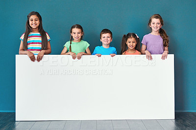 Buy stock photo Children, portrait and advertising in studio for placard, announcement and marketing with mockup space. People, smile and face on blue background for banner, branding or presentation with information