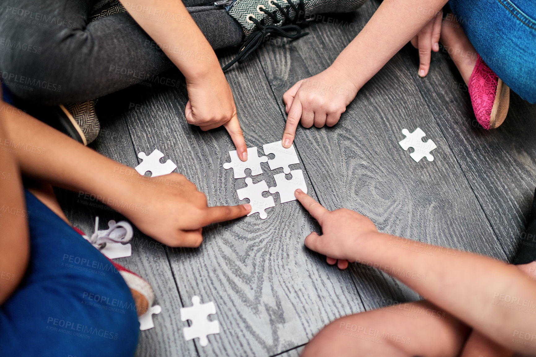 Buy stock photo Above, kids and hands with puzzle for playing, cognitive development and solution skills by floor. Teamwork, children and solidarity with jigsaw for problem solving, support and friends for bonding