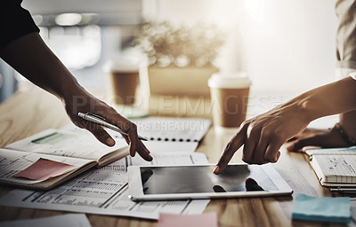 Buy stock photo Closeup shot of two businesswomen using a digital tablet while going through paperwork in an office