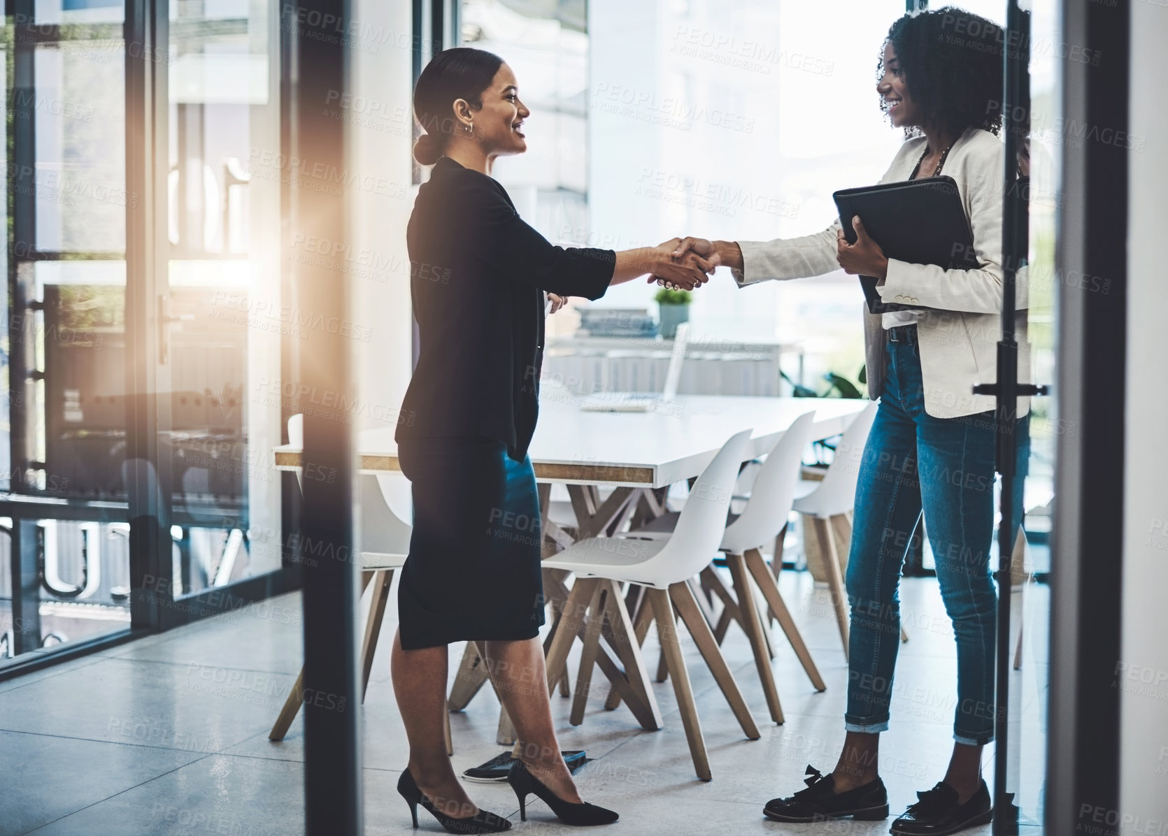 Buy stock photo Shot of two businesswomen shaking hands in an office