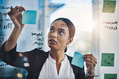 Buy stock photo Shot of a young businesswoman brainstorming notes on a glass wall in an office