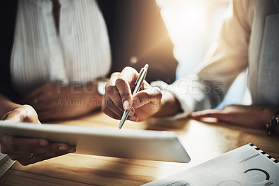 Buy stock photo Closeup shot of two businesswomen using a digital tablet while going through paperwork in an office