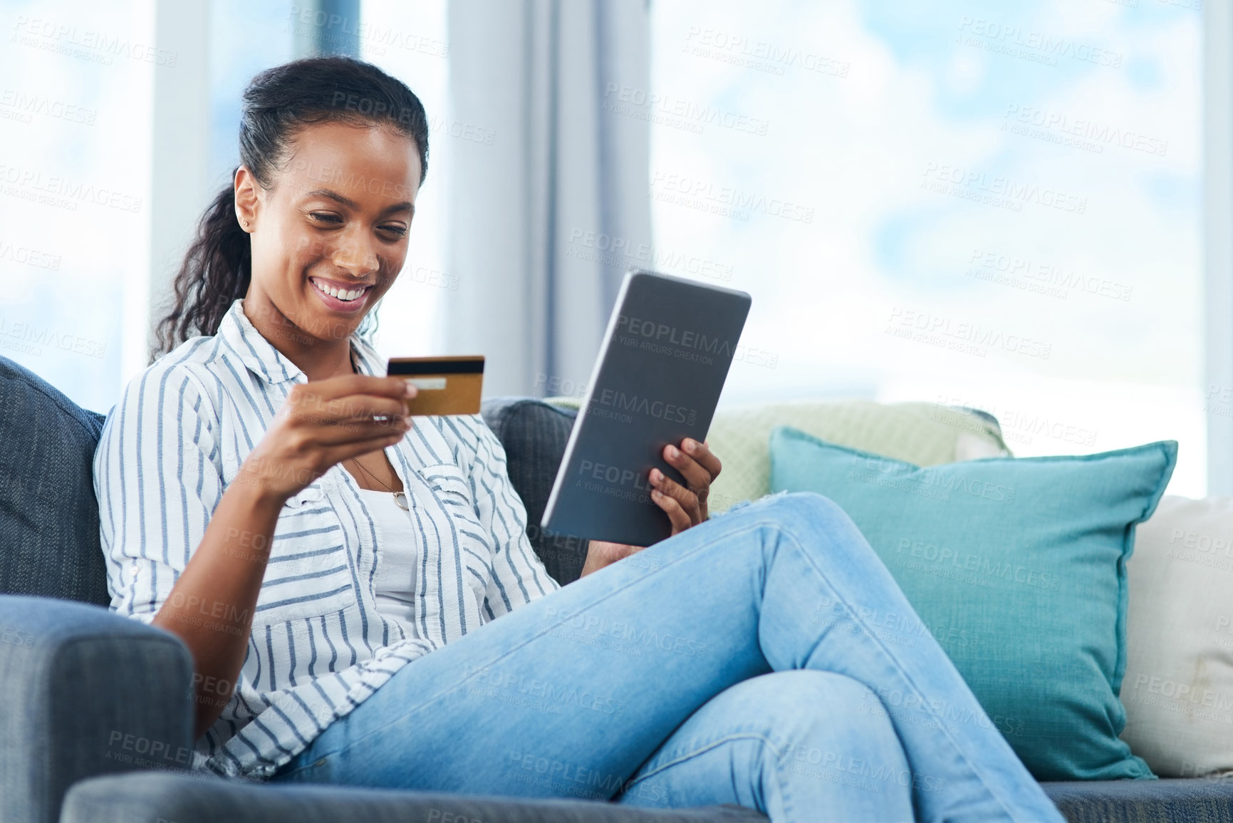 Buy stock photo Shot of a young woman using a credit card and digital tablet at home