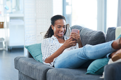 Buy stock photo Shot of a young woman texting on a cellphone at home