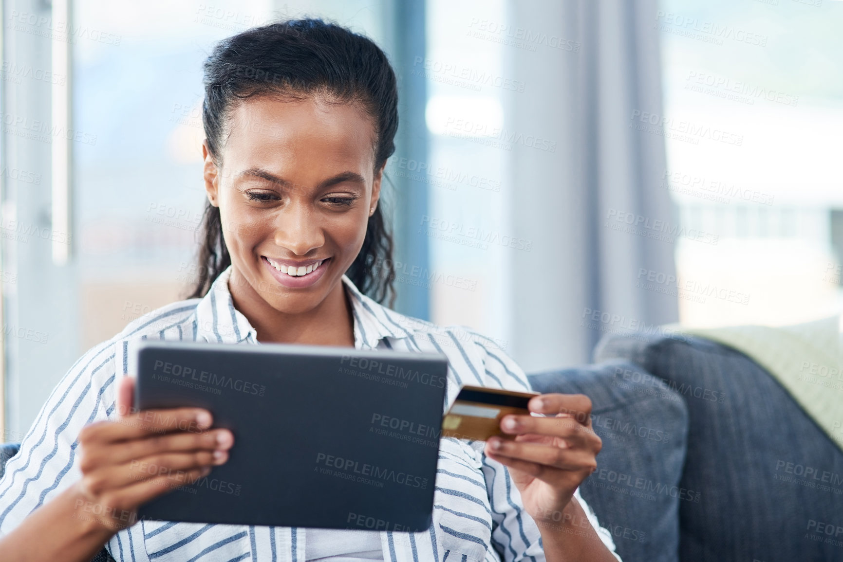 Buy stock photo Shot of a young woman using a credit card and digital tablet at home