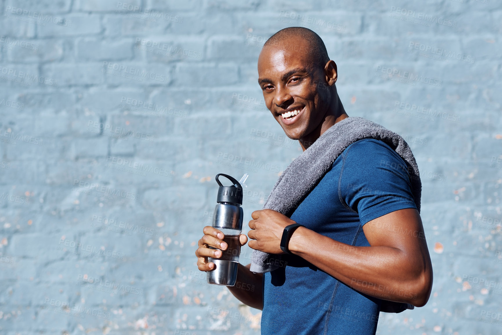 Buy stock photo Portrait of a sporty young man standing outside with his water bottle and towel