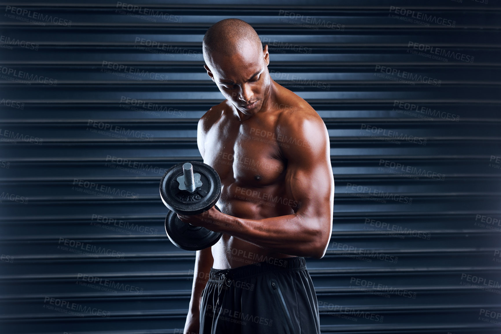 Buy stock photo Shot of a sporty young man working out with weight plates as part of his exercise routine