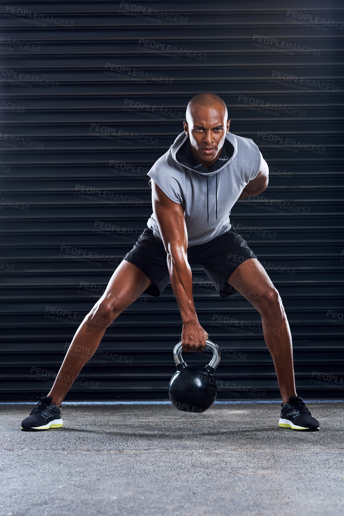 Buy stock photo Shot of a sporty young man working out with weights as part of his exercise routine