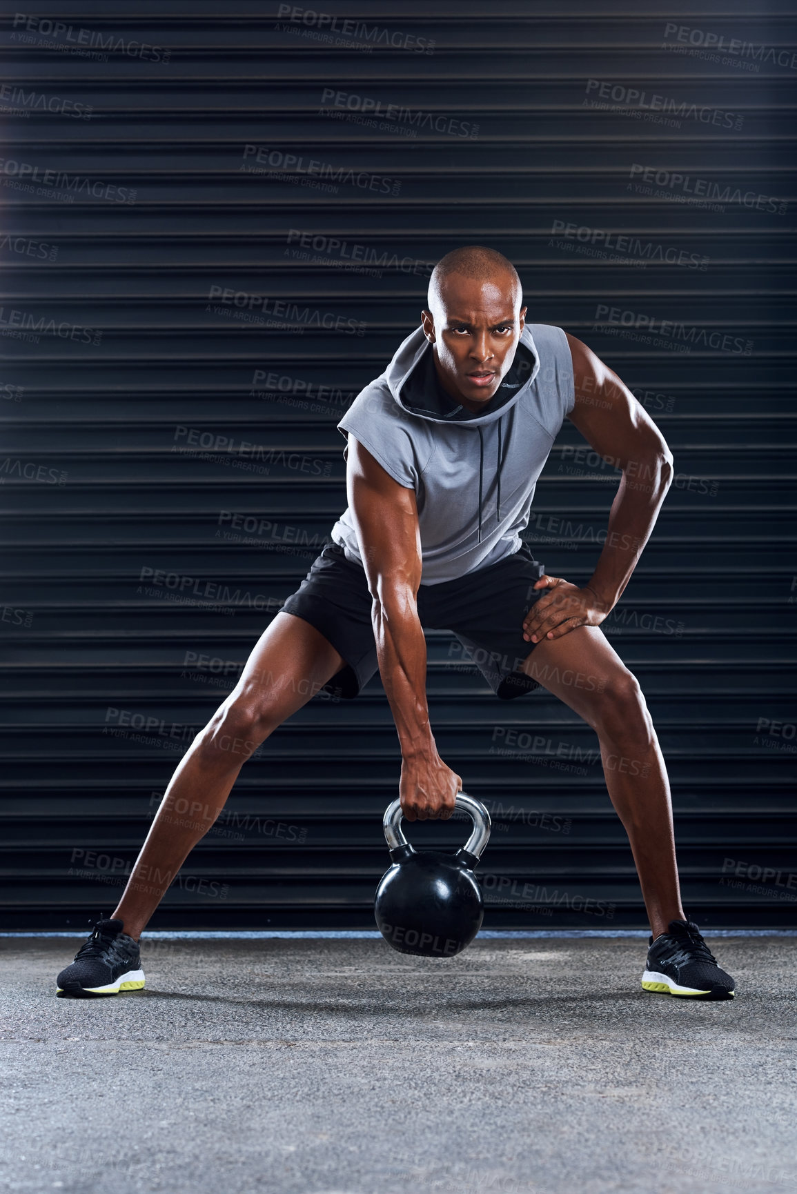 Buy stock photo Shot of a sporty young man working out with weights as part of his exercise routine
