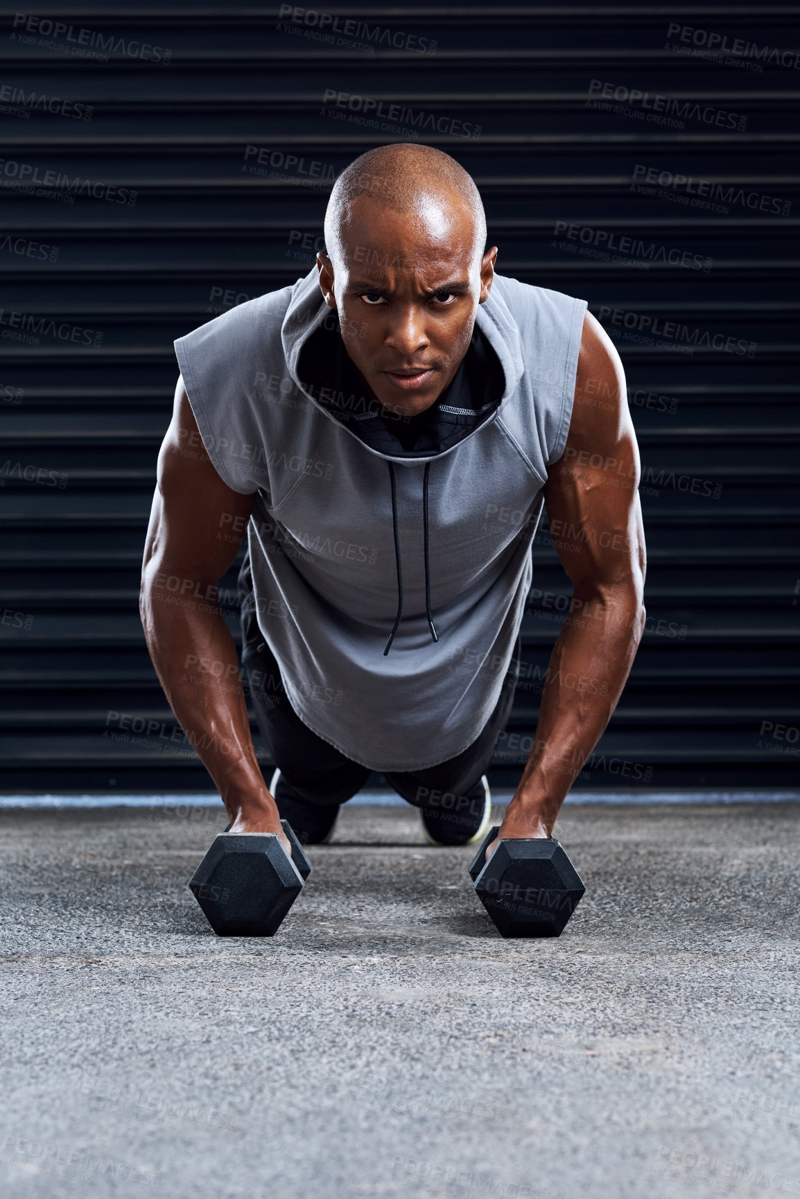 Buy stock photo Shot of a sporty young man working out with dumbbells as part of his exercise routine