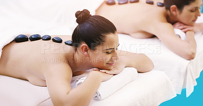 Buy stock photo Shot of two women getting hot stone massage at a spa