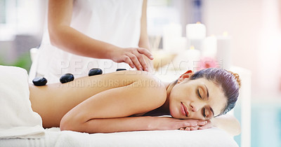 Buy stock photo Shot of a young woman getting a hot stone massage at a spa
