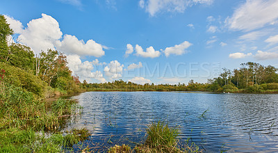 Buy stock photo Copyspace and scenic landscape of a calm and quiet lake surround by trees and scrubs and a cloudy blue sky above in Denmark. A forest with a river and lush green plants in a remote location in nature