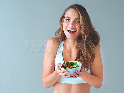Buy stock photo Studio shot of a healthy young woman smiling and posing with a salad against a grey background