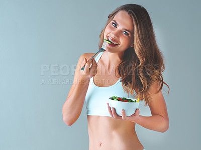 Buy stock photo Studio shot of a healthy young woman eating a salad against a grey background