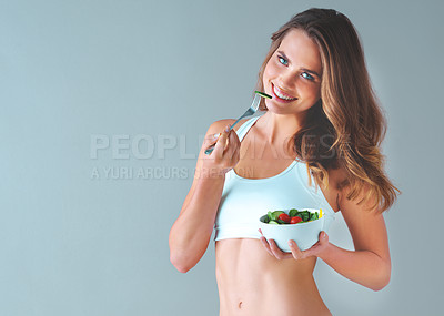 Buy stock photo Studio shot of a healthy young woman smiling and posing with a salad against a grey background