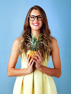 Buy stock photo Studio shot of a young woman holding a pineapple against a blue background