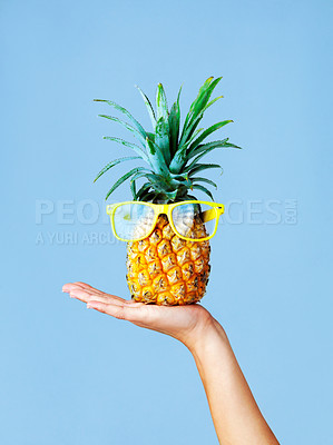 Buy stock photo Cropped shot of a woman holding a pineapple with glasses on against a blue background