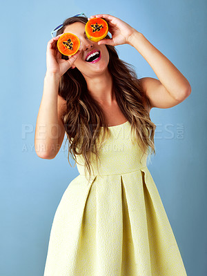 Buy stock photo Happy, papaya on eyes and woman on blue background for healthy eating, nutrition and detox for wellness. Food, smile and person with fruit for organic diet, wellbeing and natural vitamins in studio