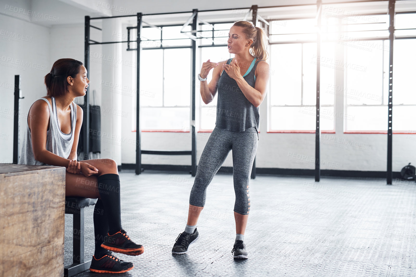 Buy stock photo Woman, fitness and personal trainer with conversation for workout, training or indoor exercise at gym. Active female person or coach explaining warm up routine, session or discussion at health club