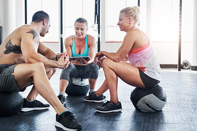 Buy stock photo Shot of a group of people using a digital tablet at the gym