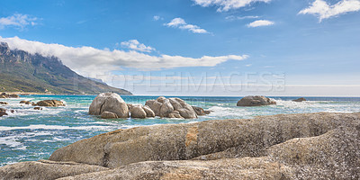 Buy stock photo Waves crashing onto a rocky shore and a seascape view of the ocean with blue sky copy space in Camps Bay, Cape Town, South Africa. Calm, serene, tranquil beach and relaxing nature scenery