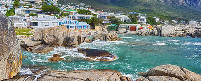 Buy stock photo Scenic view of sea, rocks and residential buildings in Camps Bay Beach, Cape Town, South Africa. Tidal ocean waves washing over shoreline rocks and boulders. Overseas travel and tourism destination